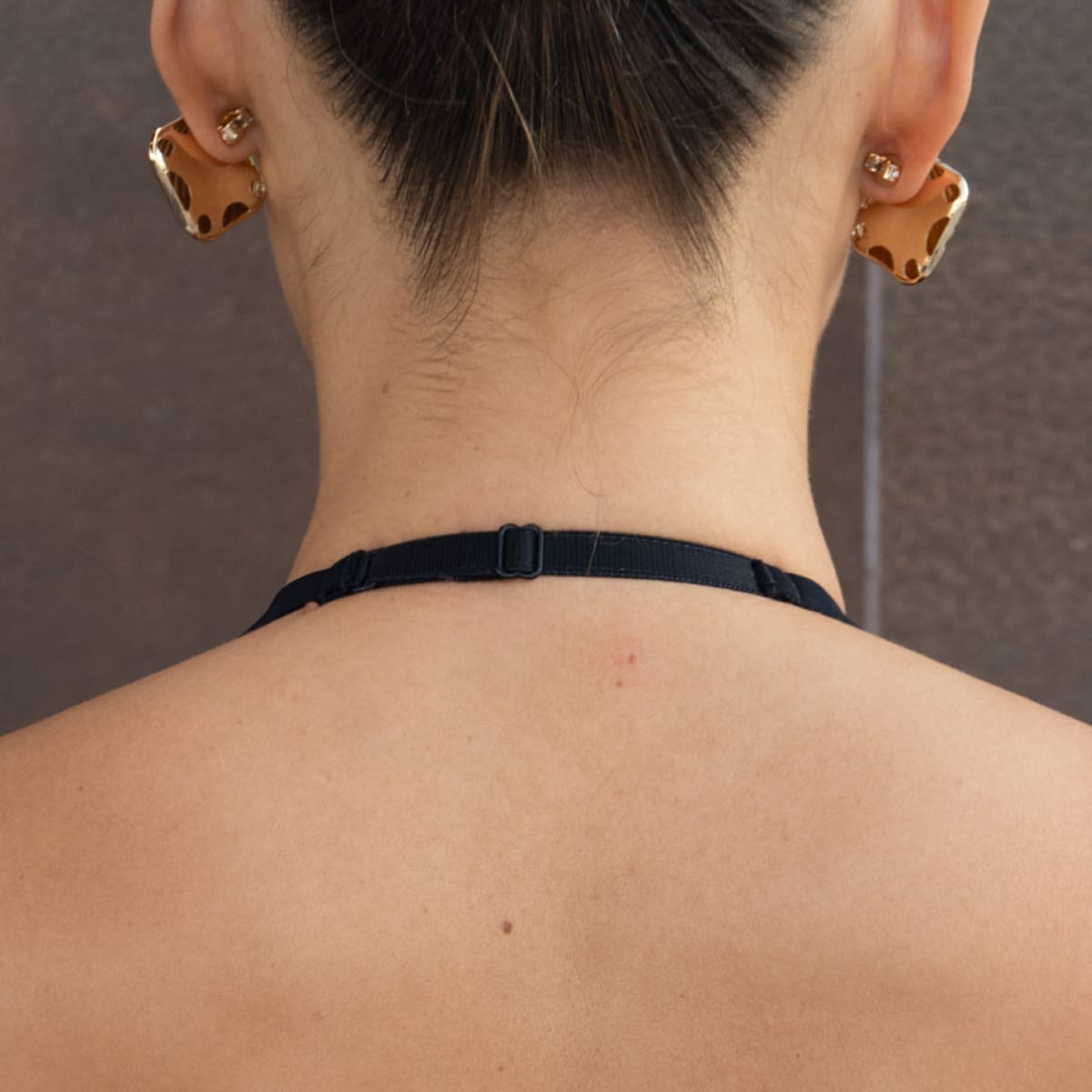 Black halter top with adjustable neck strap and clasp closure, shown from back view.