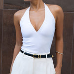 White halter plunge neck top with sleeveless design and fitted silhouette.