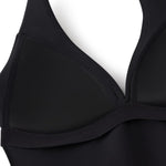 Black halter top with plunging neckline and structured cups, shown close-up on front bodice.