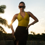 Yellow halter top with deep V neckline and black skirt worn by model outdoors.