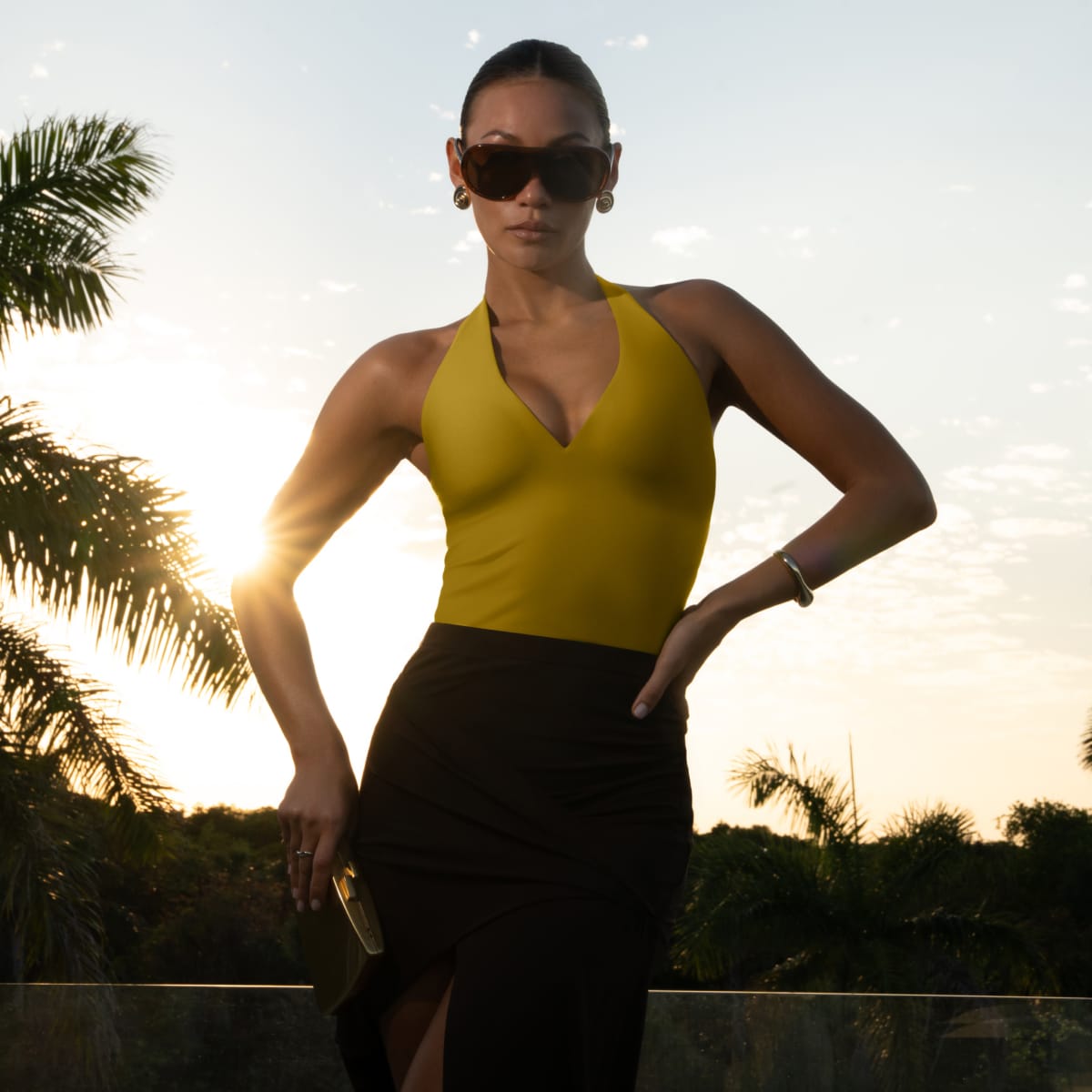 Yellow halter top with deep V neckline and black skirt worn by model outdoors.