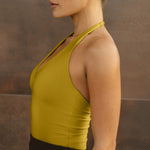 Yellow halter top with deep V neckline and open back design, shown on model in side profile.