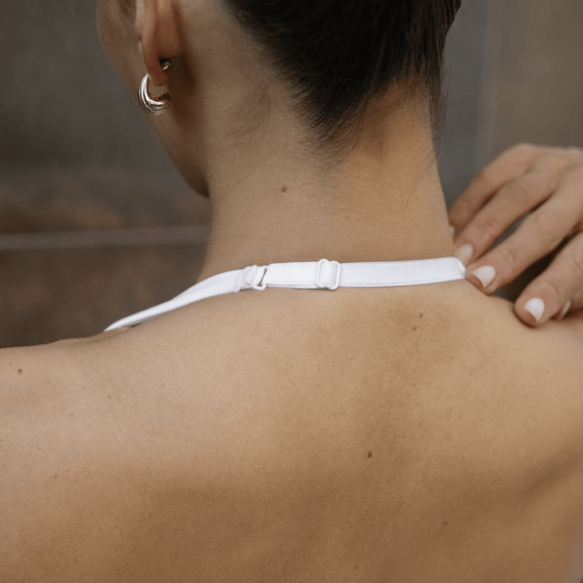 White halter top with adjustable neck strap shown from behind on a model.